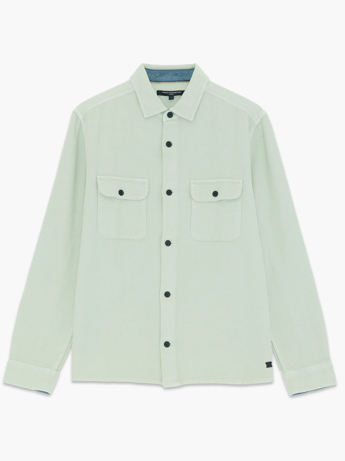 A man wearing a sage green over shirt with long sleeves. a pointed collar and a button down fastening.