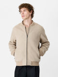 A man wearing a sand bomber jacket with long sleeves, a crew neck and a zip down front.
