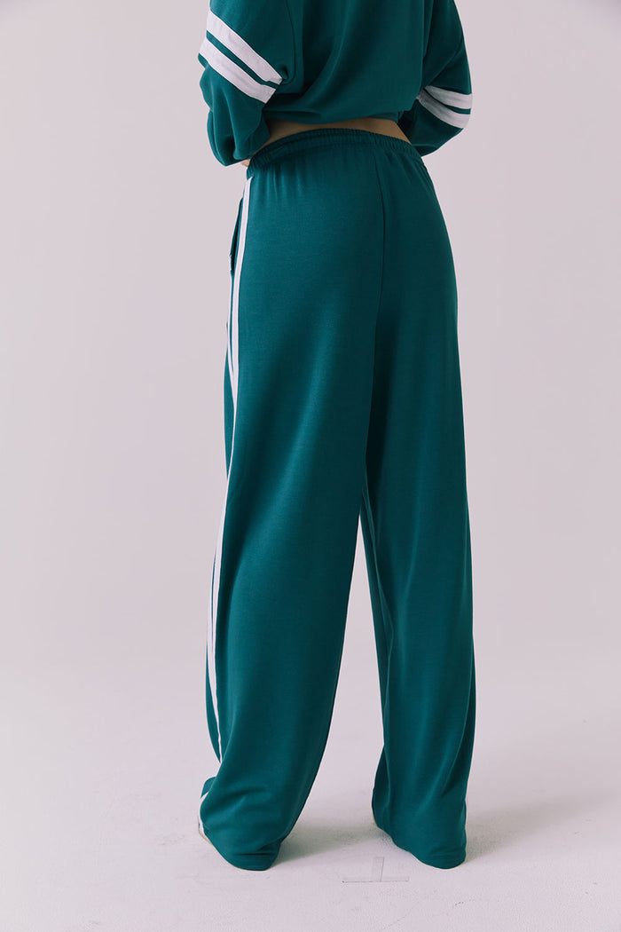 Saltwater Luxe Sandi Joggers in Teal with White side stripes shown from the back highlighting the relaxed fit and elastic waistband with the matching Cornell Pullover partially visible