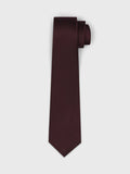 Burgundy sangria tie coiled on light grey background