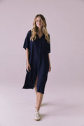 Full body front walking view of the Chaser Seaside Navy Button Up Dress with a relaxed drape and side slit