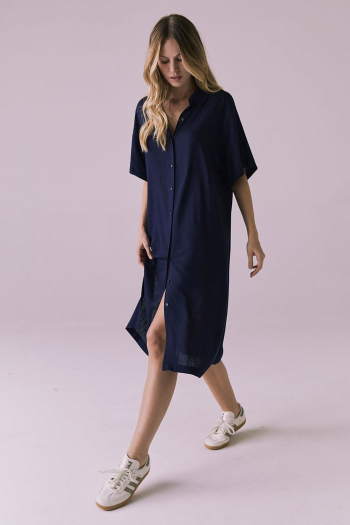 Full body walking view of the Chaser Seaside Navy Button Up Dress with a soft button front and easy movement
