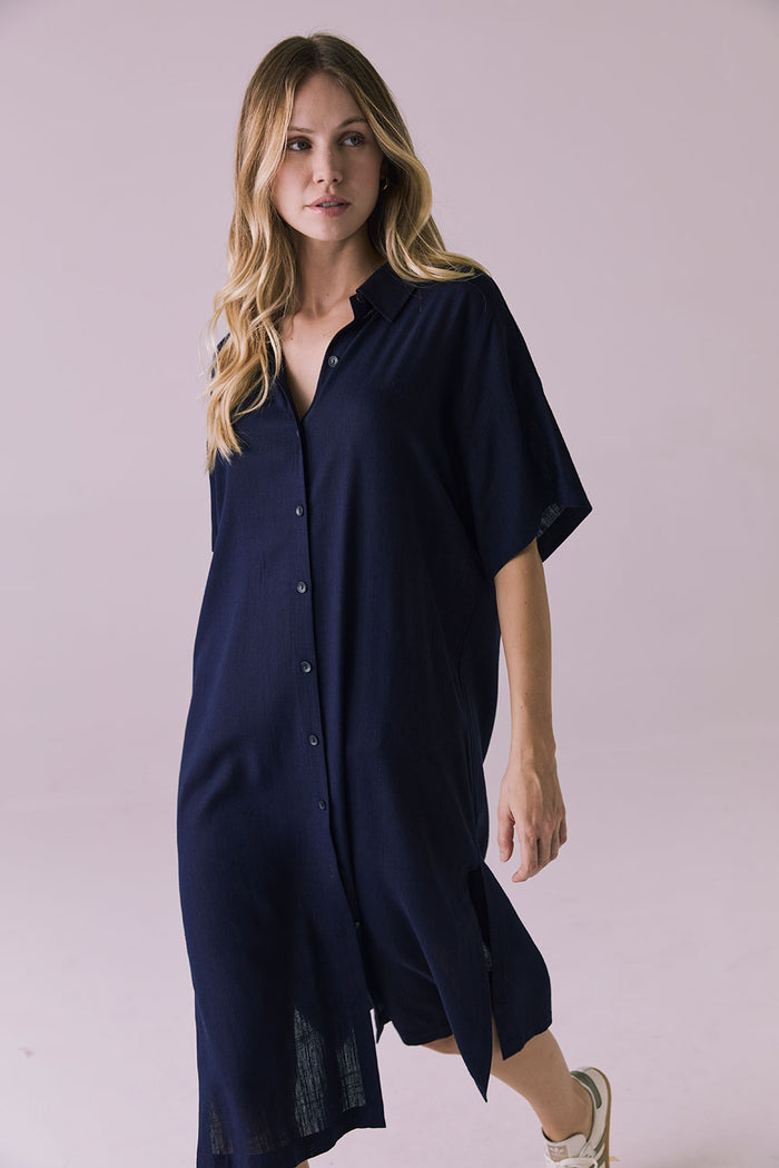 Full body mid stride view of the Chaser Seaside Navy Button Up Dress highlighting the breezy side slit