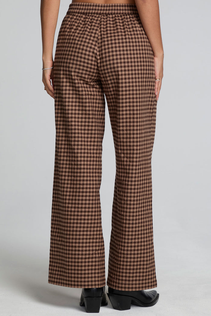 Back view of a woman wearing the Chaser Seren Choco Check Pants on a neutral background with hands at sides