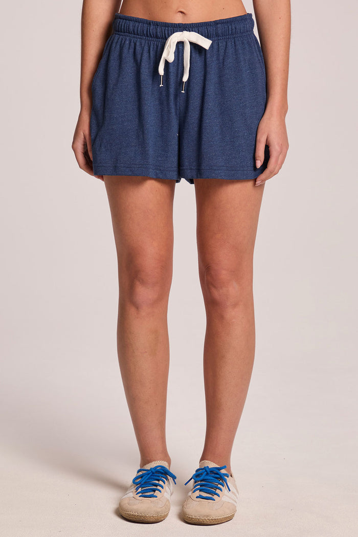 A front view of a woman wearing the Chaser Serena Admiral Shorts on a neutral background with sneakers