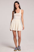 A full body front view of a woman wearing the Chaser Coconut Milk Serve Mini Skort and matching tank top on a neutral background