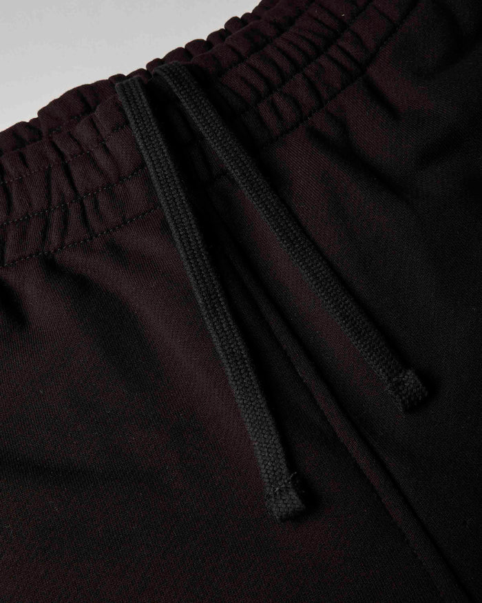 Close-up of dark burgundy or very deep wine pants with a black drawstring waistband, showing the fabric texture and elasticized waist.