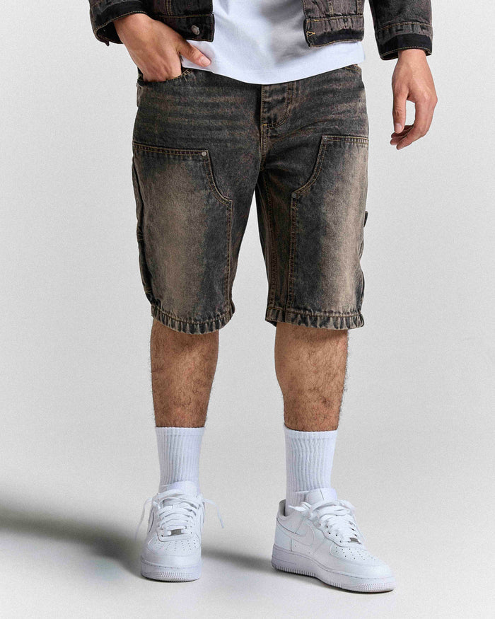 Model wearing regular fit black rust washed denim jorts featuring Hoodrich logo embroidery on the pocket.
