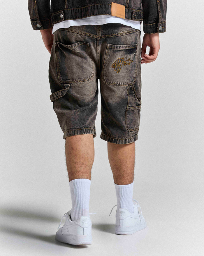 Model seen from behind wearing regular fit black rust washed denim jorts.