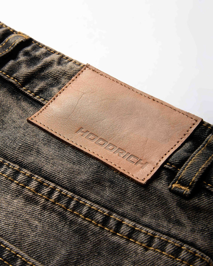 Close-up of the metal button and rivet detailing on the regular fit black rust washed denim jorts.