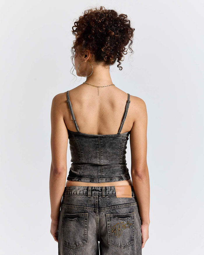 Model seen from behind wearing a fitted black denim corset top and matching jeans.