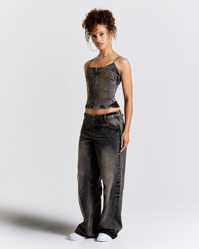 Model wearing a fitted black denim corset top and matching baggy jeans with yellow Hoodrich logo embroidery.