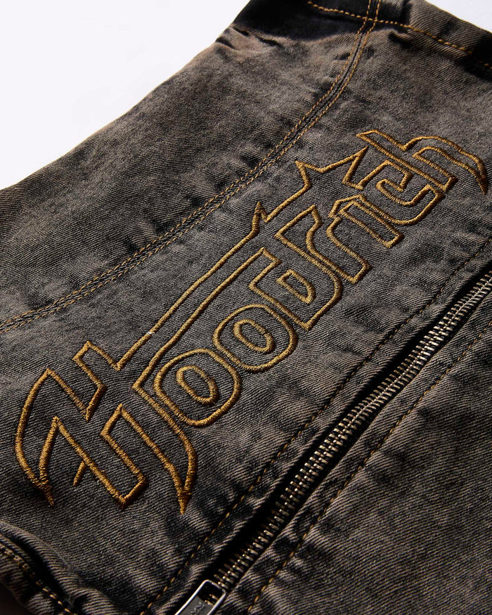 Close-up of the yellow Hoodrich logo embroidery on the black denim fabric of the corset top.