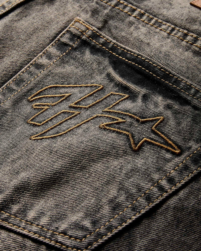 Close-up of a denim jacket with an embroidered logo on the pocket.