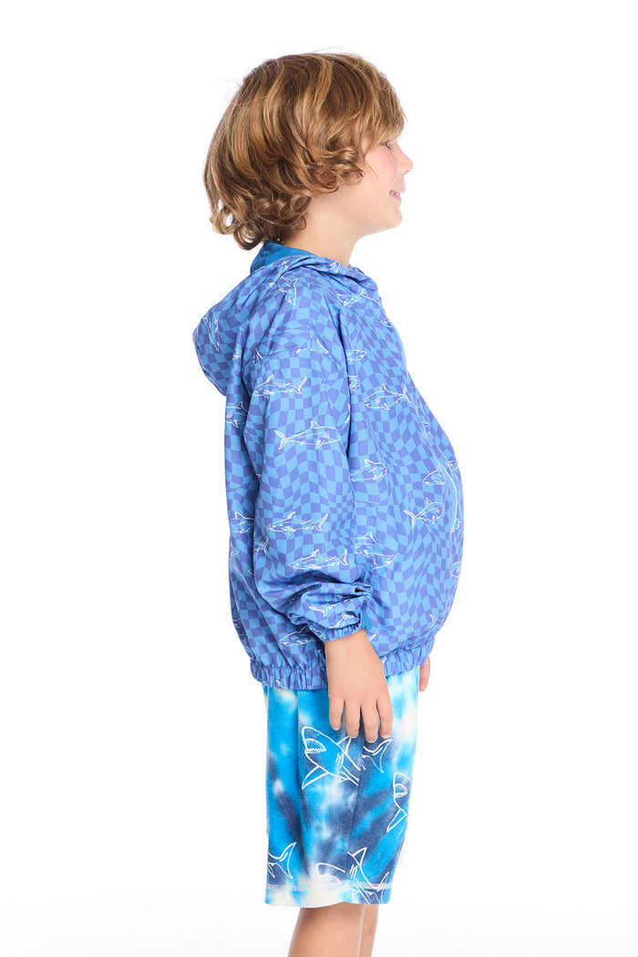 Side view of boy wearing the Chaser Kids Shark Check Zip Up Hoodie showing relaxed fit and hood detail, styled with Shark Bite Shorts and navy sneakers on a white background