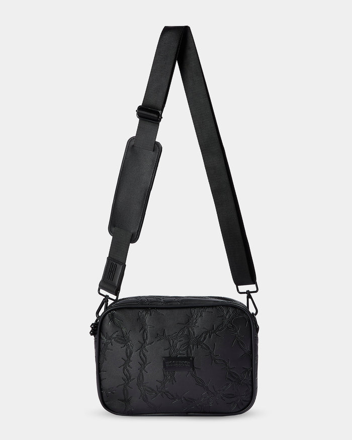 Black quilted crossbody bag with a strap on a light gray background