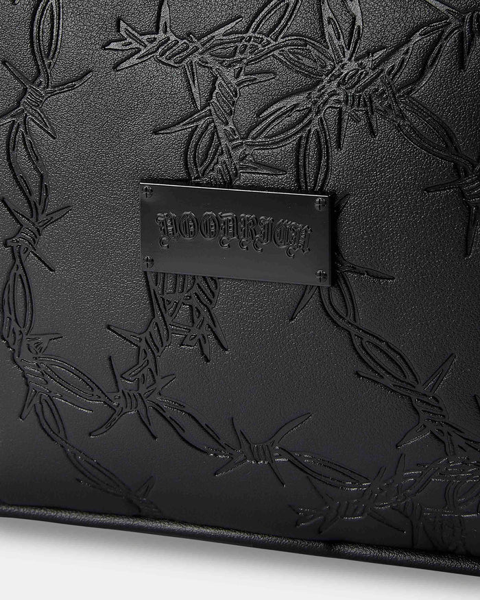Black leather clutch with embossed design and visible brand name on a white background