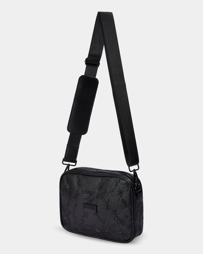 Black crossbody bag with floral pattern on a light gray background