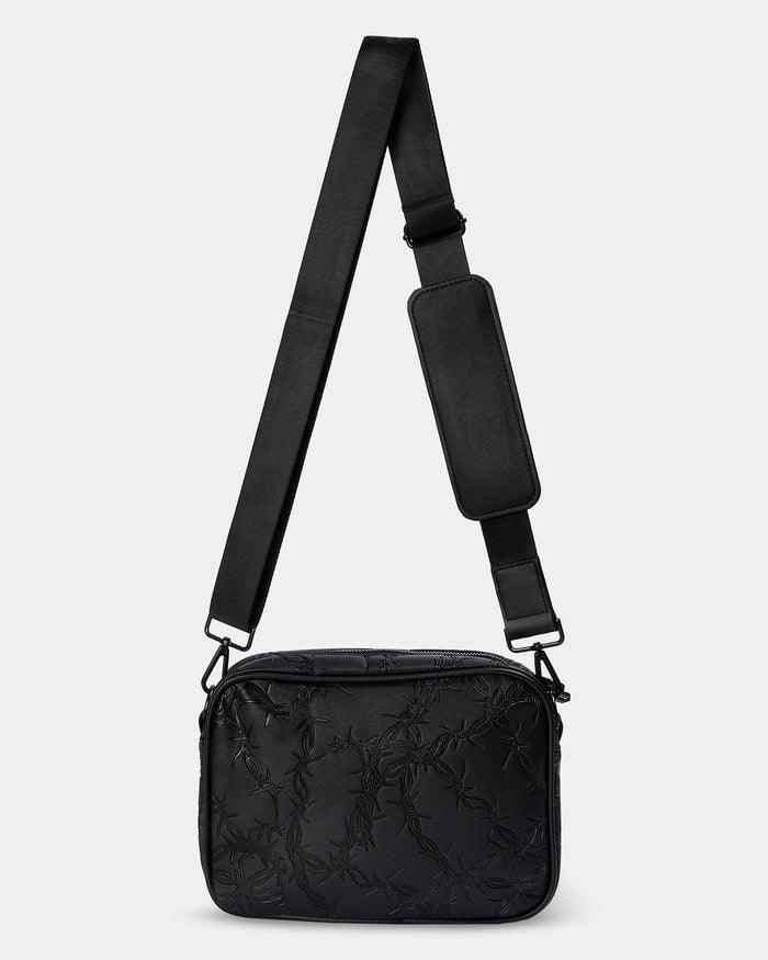 Black crossbody bag with a strap on a light gray background