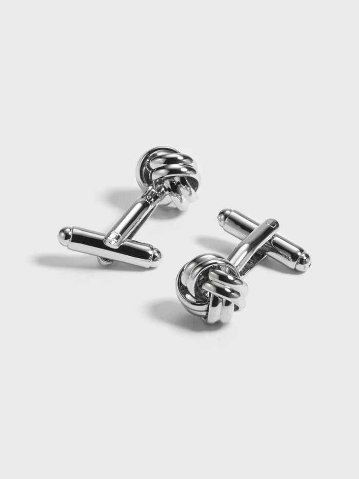 Polished silver knot-shaped cufflinks, pair on grey background