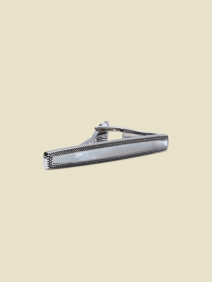 Silver tie bar with mother-of-pearl inlay and milgrain trim on cream background