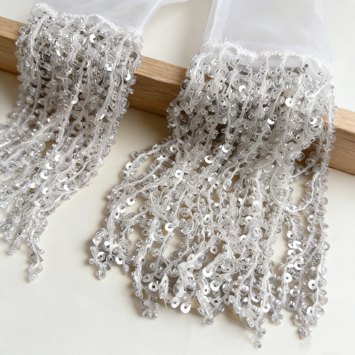Silver sequin fringe bridal gloves with sheer fabric and sparkling tassel cuffs for wedding ceremony and evening styling.