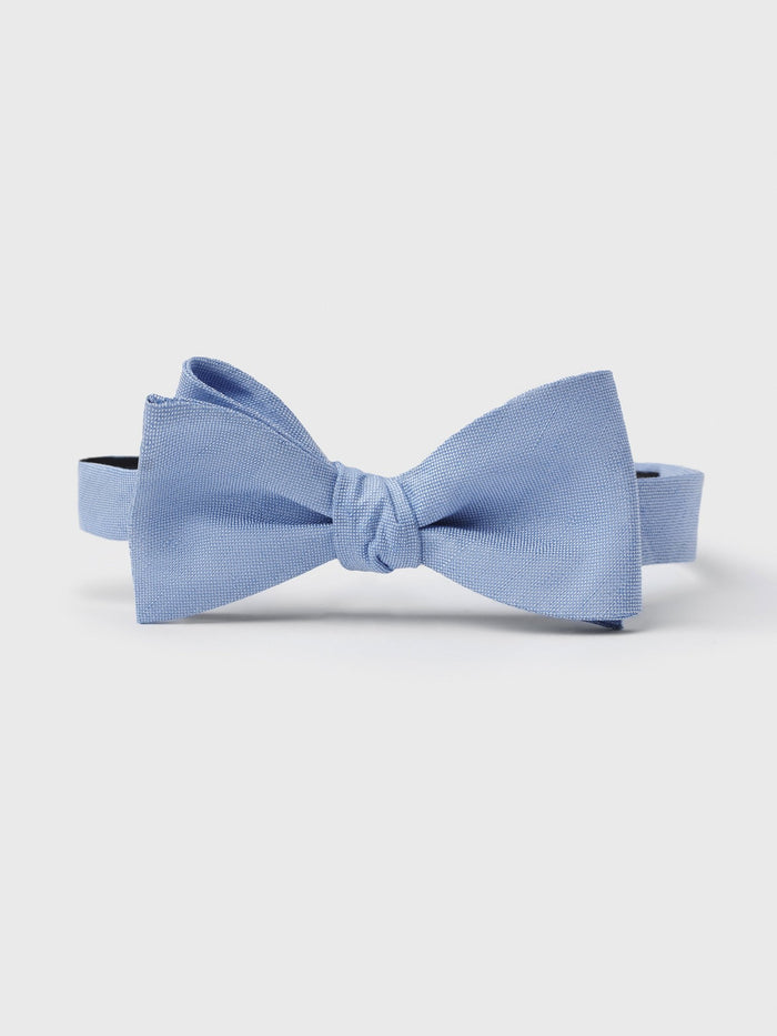 Sky blue linen silk bow tie, tied, on light grey background