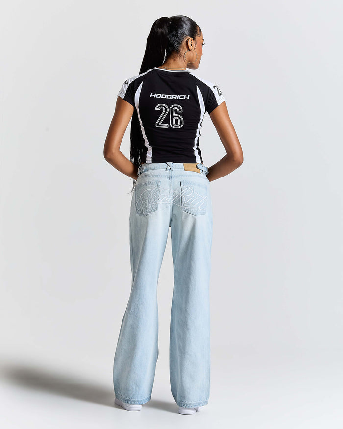Person wearing a black t-shirt with white text and light blue jeans on a plain background