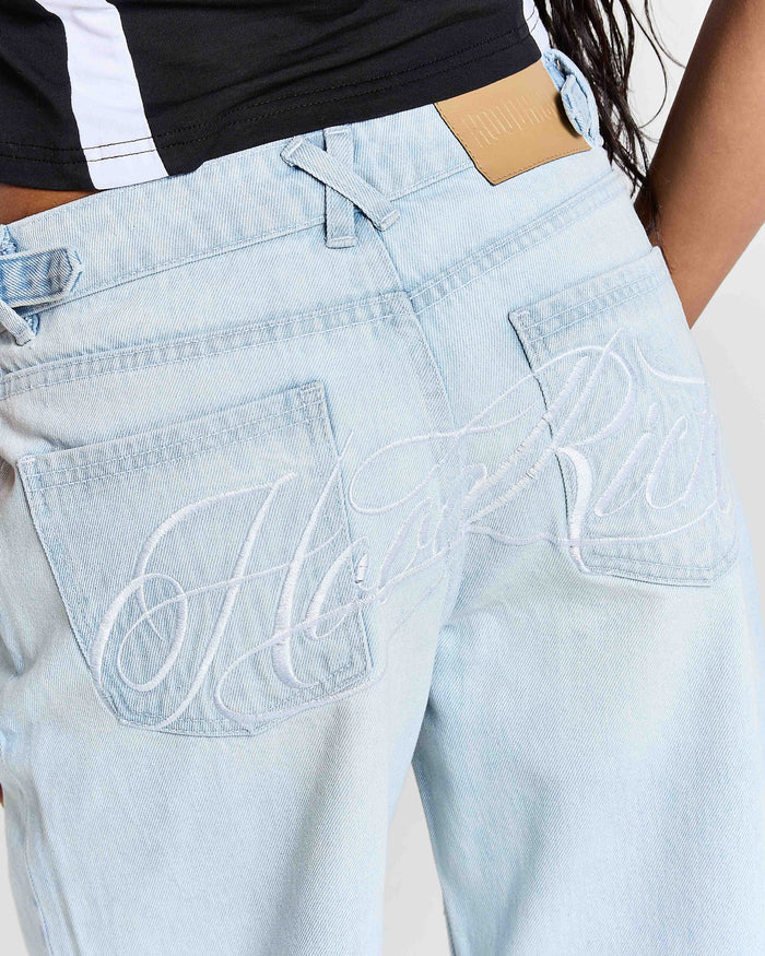 Light blue jeans with brand logo on pocket against a neutral background