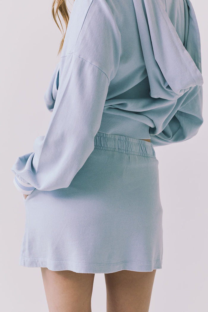 Chaser Soleil Blue Bird Mini Skort in Blue Bird styled with the matching Abilene Zip Up Hoodie showing the elastic waistband and smooth back silhouette