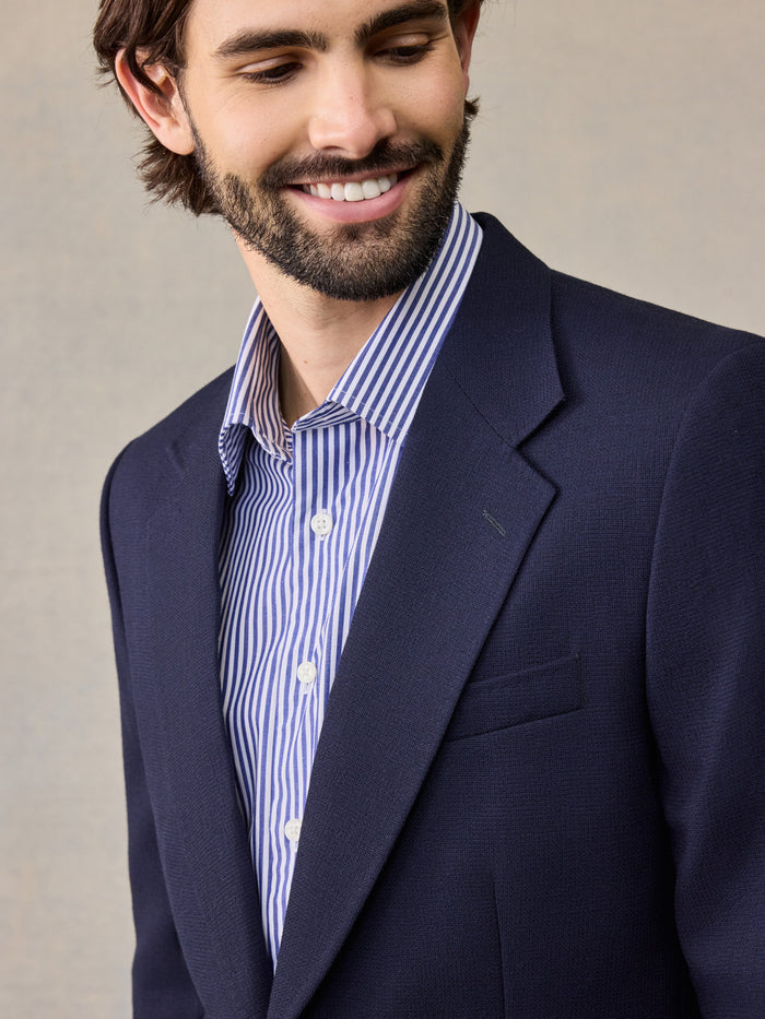 Close-up of man smiling in navy sportcoat with notch lapel and striped shirt