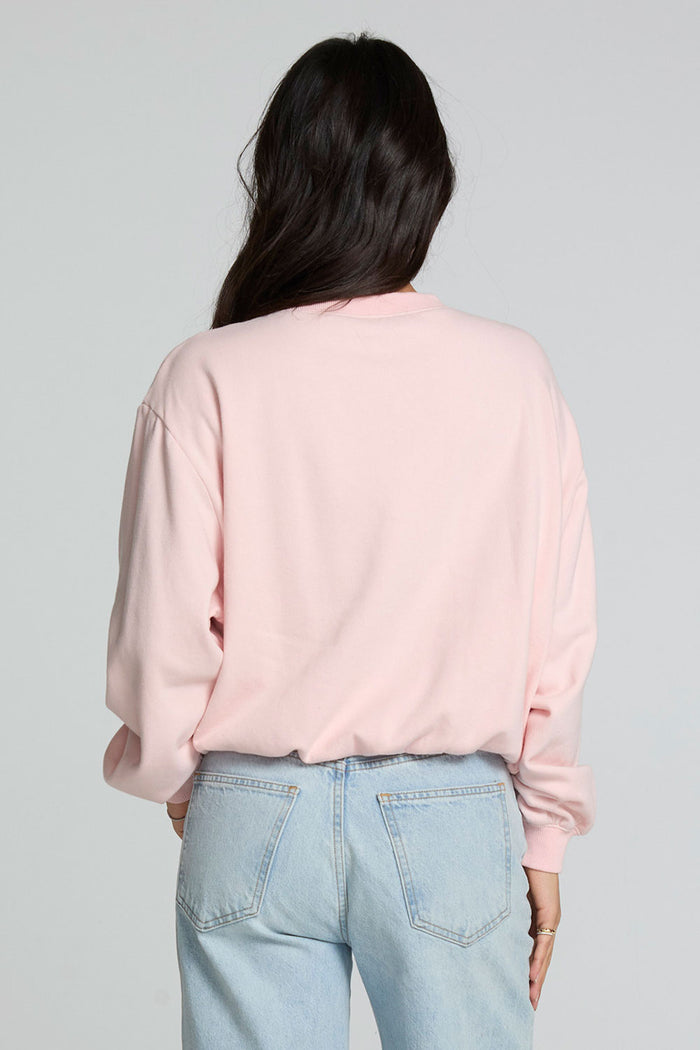 Back view of a woman wearing the Chaser Sporty Patches Long Sleeve Top and jeans on a neutral background