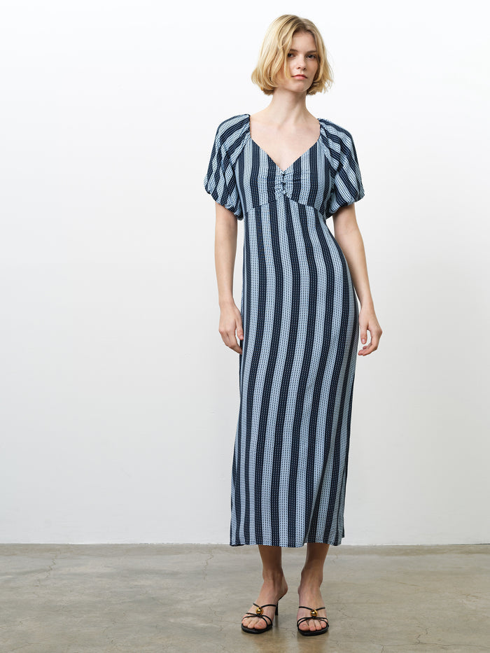 Woman wearing a blue spot and striped midi dress, with puff sleeves, a sweetheart neckline and an empire waist