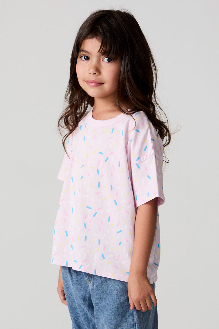 Side view of a girl wearing the Chaser Sprinkle Party Tee on a neutral background