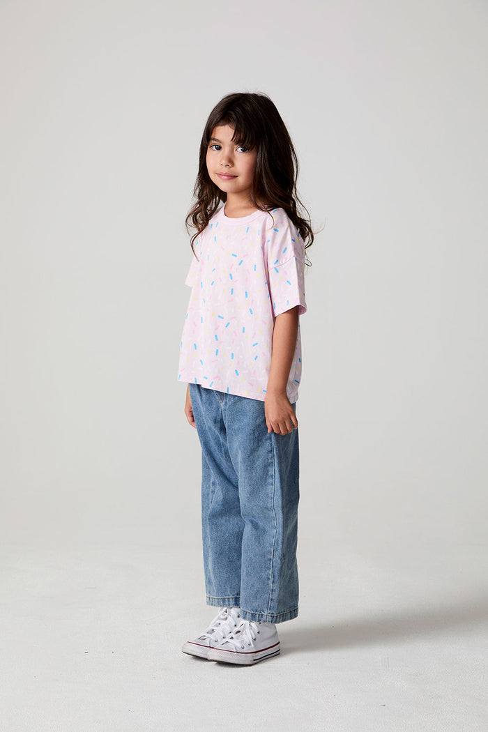 Full body side view of a girl wearing the Chaser Sprinkle Party Tee on a neutral background