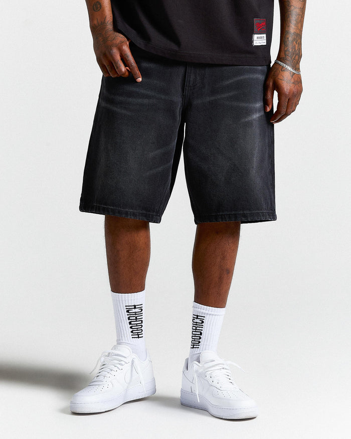 Person wearing black shorts, white sneakers, and socks with text on a plain background
