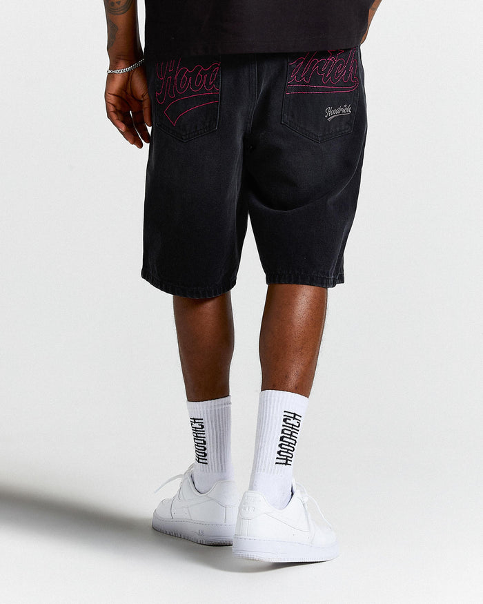 Person wearing black shorts with red embroidery and white socks with text, standing against a white background