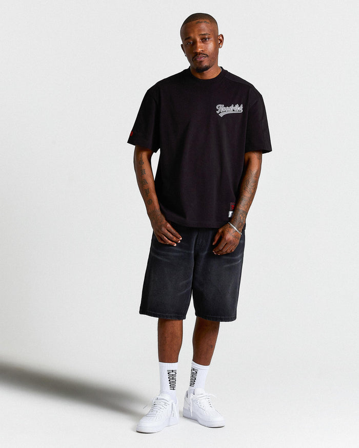 Man wearing a black t-shirt and denim shorts on a white background