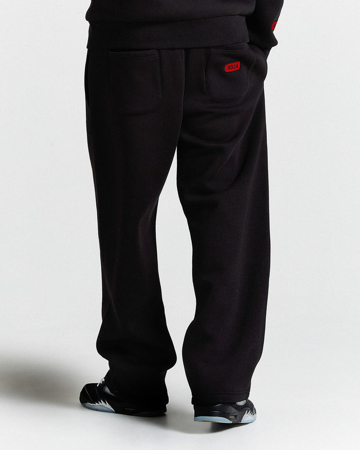 Black pants with a red tag on a white background
