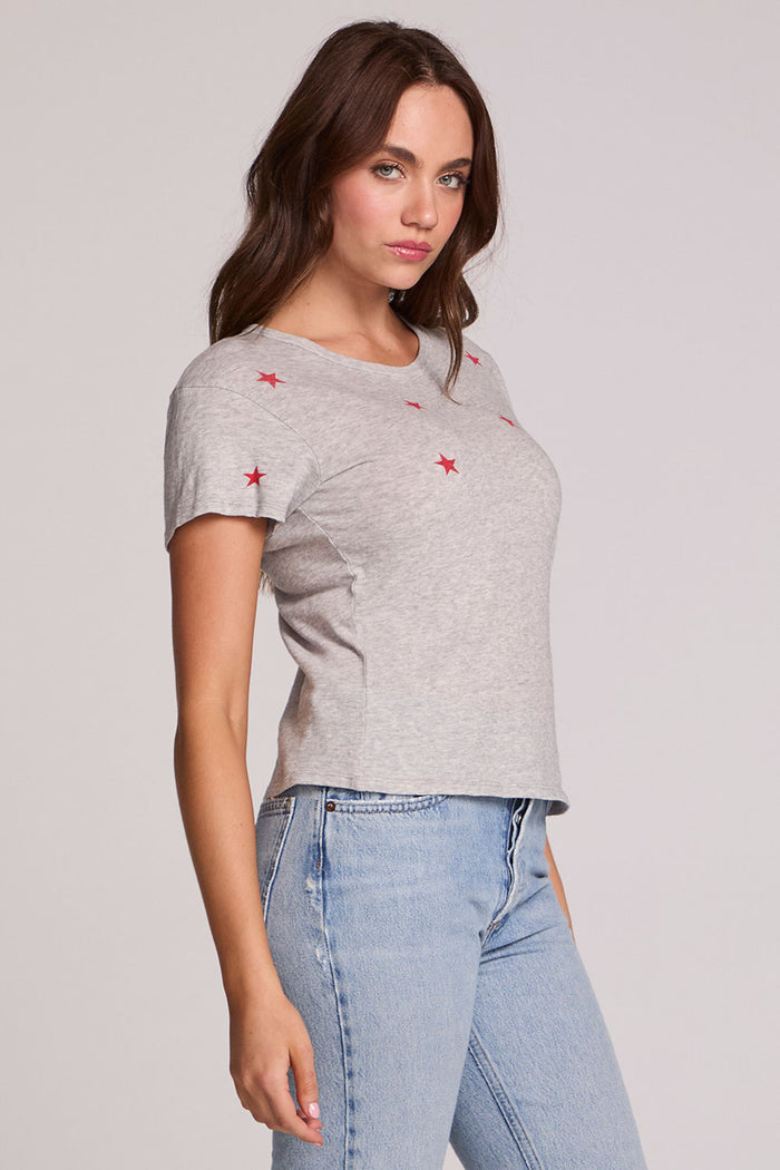 Side angle view of a woman wearing the Chaser Star Setter Cropped Tee on a neutral background with jeans