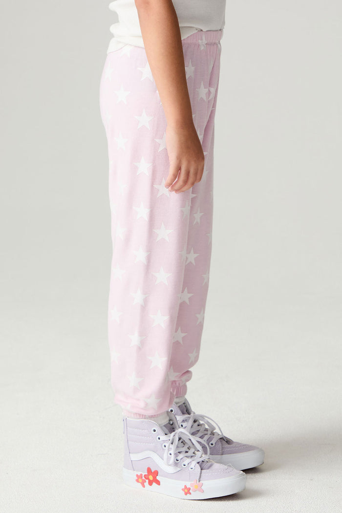 Side view of a girl wearing the Chaser Stars Allover Girls Jogger on a neutral background with sneakers