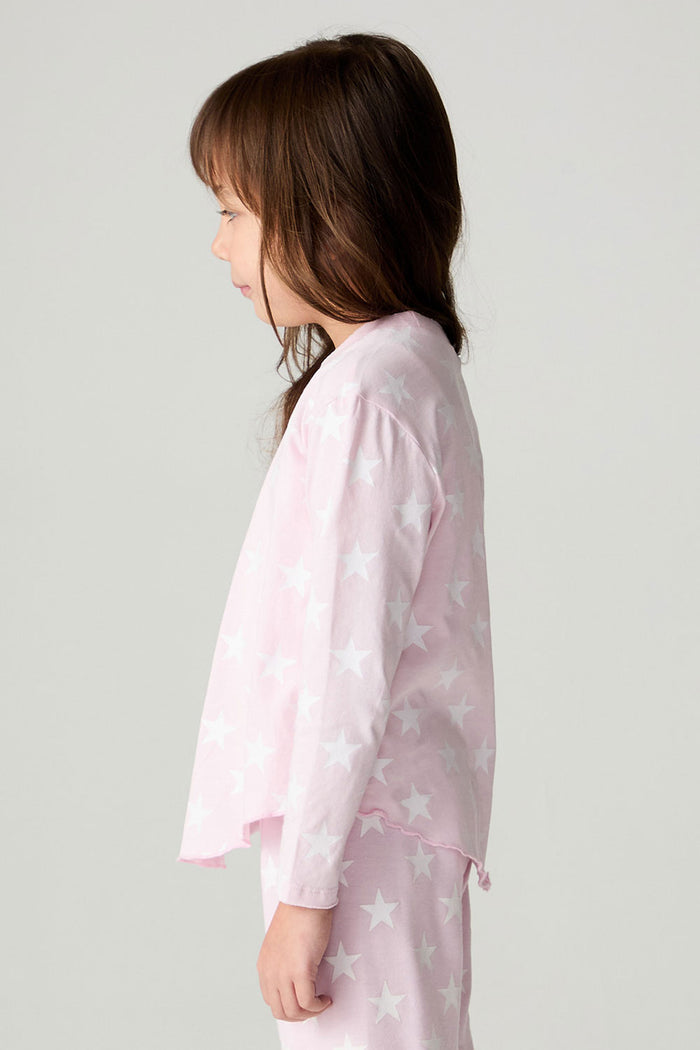 Side view of a girl wearing the Chaser Stars Allover Girls Tee on a neutral background with long sleeve top
