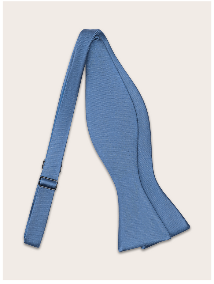 Steel blue bow tie untied against a light neutral background