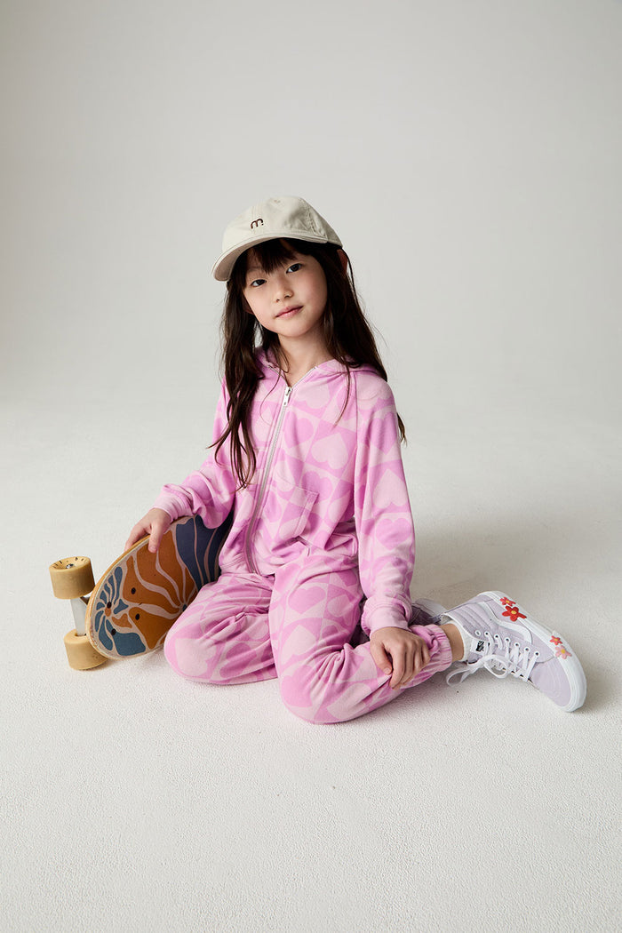 Front view of a girl wearing the Chaser Straight To The Heart Girls Hoodie on a neutral background wearing a hat and holding a skateboard