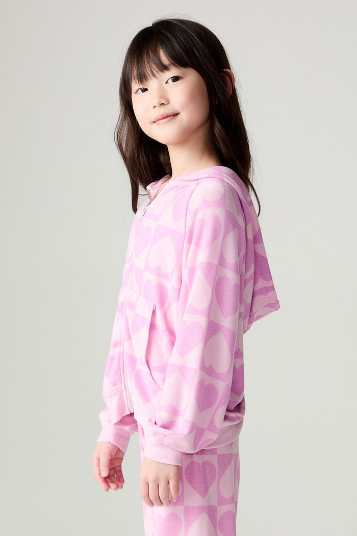 Side angle view of a girl wearing the Chaser Straight To The Heart Girls Hoodie on a neutral background with matching pants