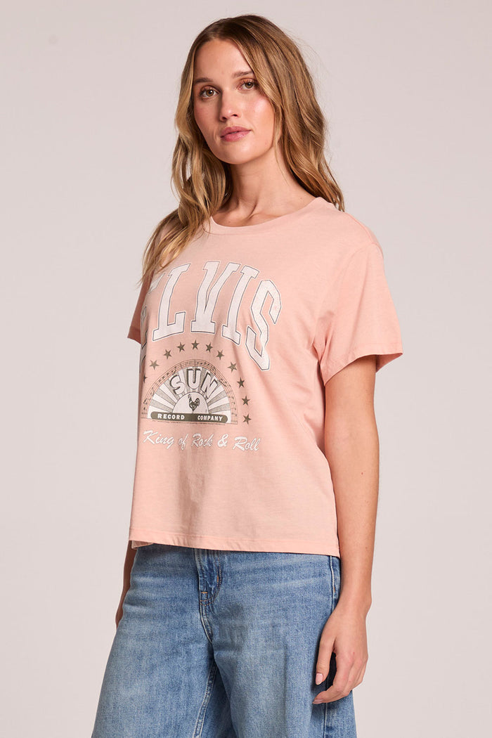 Side angle view of a woman wearing the Chaser  Sun Records Elvis Collegiate Tour Tee on a neutral background with arms at her sides