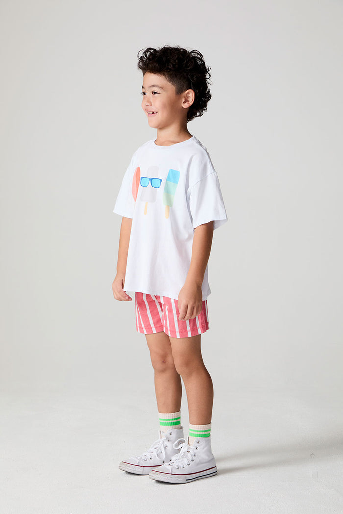 Full body side angle view of a boy wearing the Chaser Sunglass Pop Tee  on a neutral background