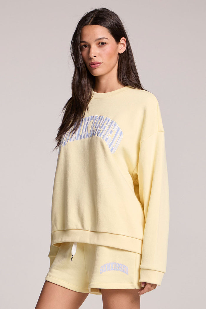 Side angle view of a woman wearing the Chaser  Sunkissed Long Sleeve on a neutral background with arms at her sides