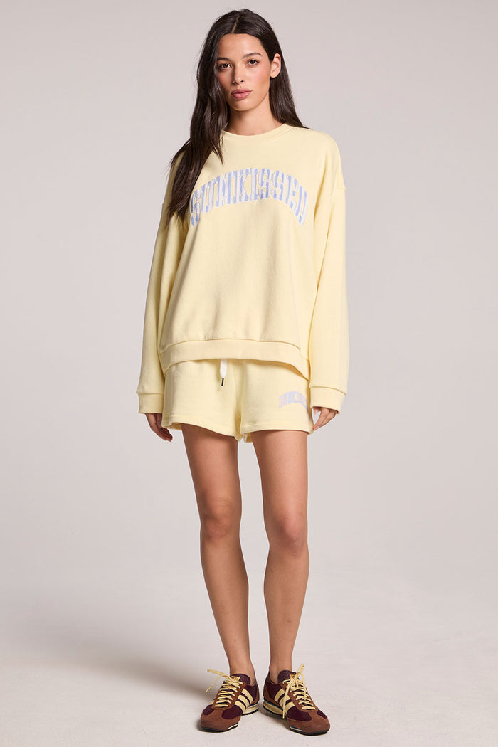 Front  view of a woman wearing the Chaser  Sunkissed Long Sleeve and sneakers on a neutral background