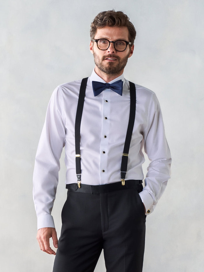 Man in white shirt with black gold-clip suspenders and navy bow tie, front view